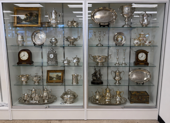 Glass display case filled with antique silver and vintage collectible